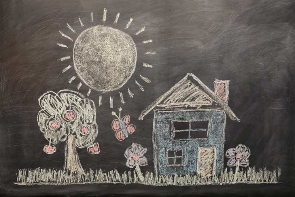 chalkboard drawing by children of a house, sun and trees