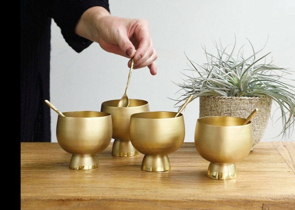 a person stirring four golden goblets