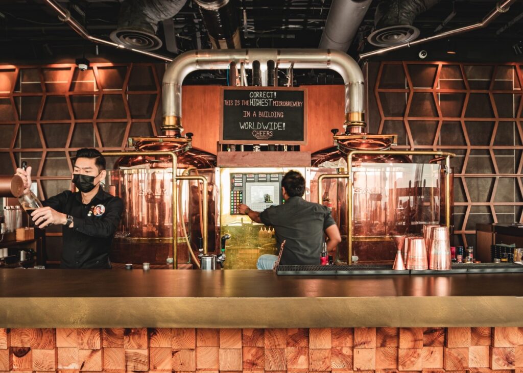 two people behind a copper finished bar at a distillery