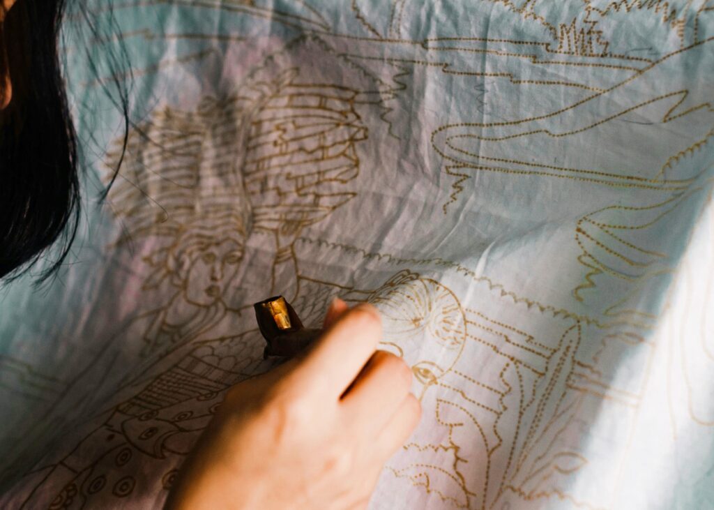 a person creating batik on a fabric