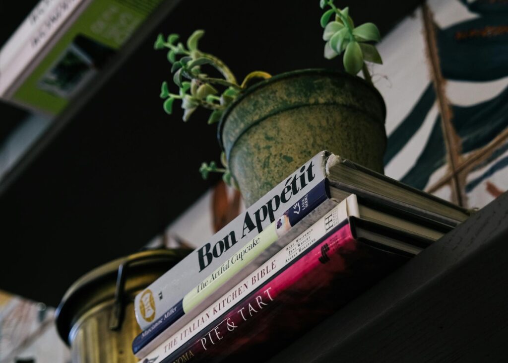 a stack of books on a shelf with a planter on top