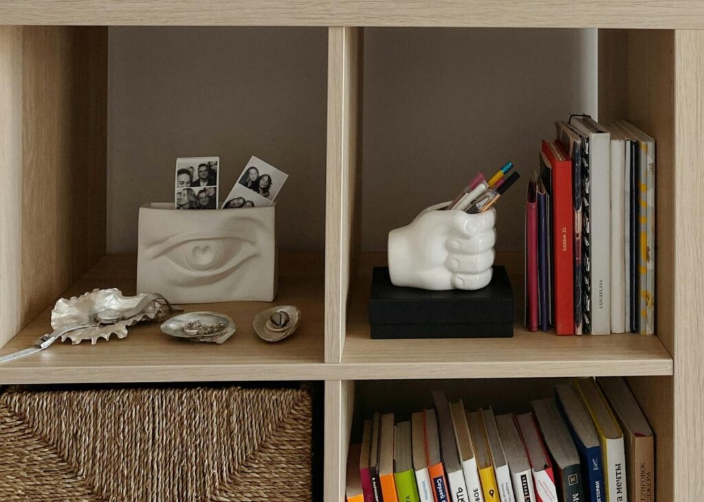 open shelf with books, a storage container and other art objects