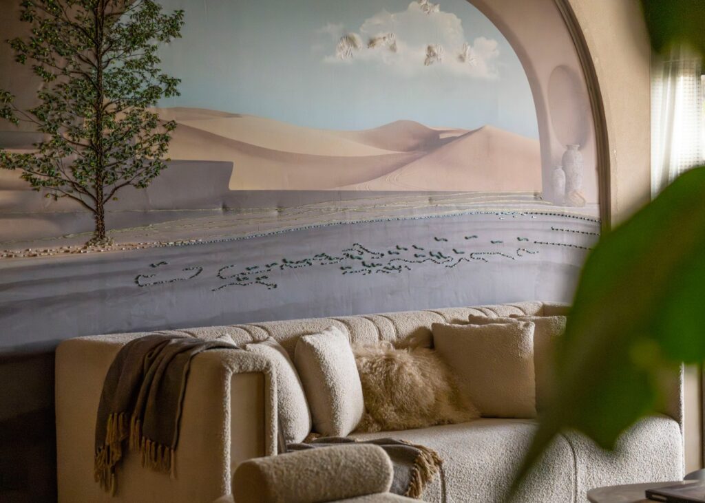 a cream toned sofa in front of a wall mural of a desert