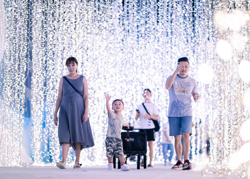 a family walking through a tunnel of fairy lights