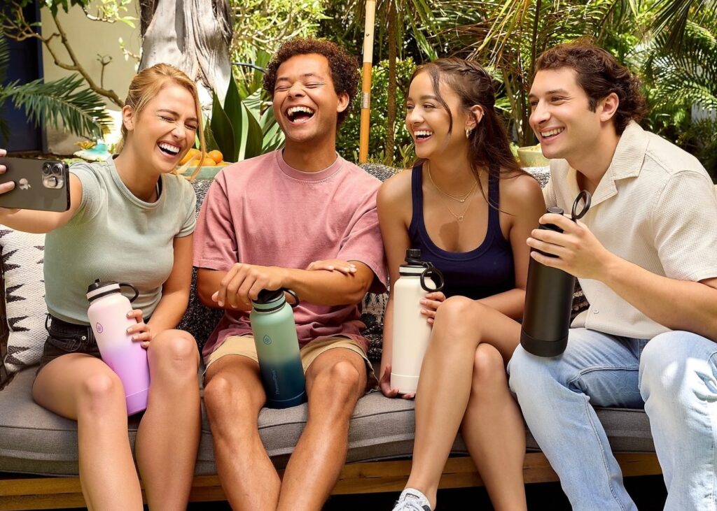 two men and two women taking a selfie and holding a water bottle each