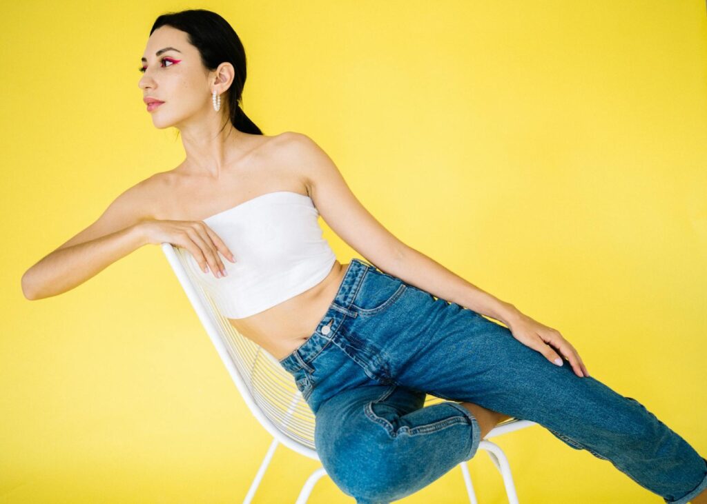 woman sitting in blue trousers and white tank top