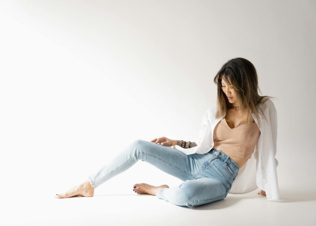 a model wearing blue trousers and beige top sitting on the ground