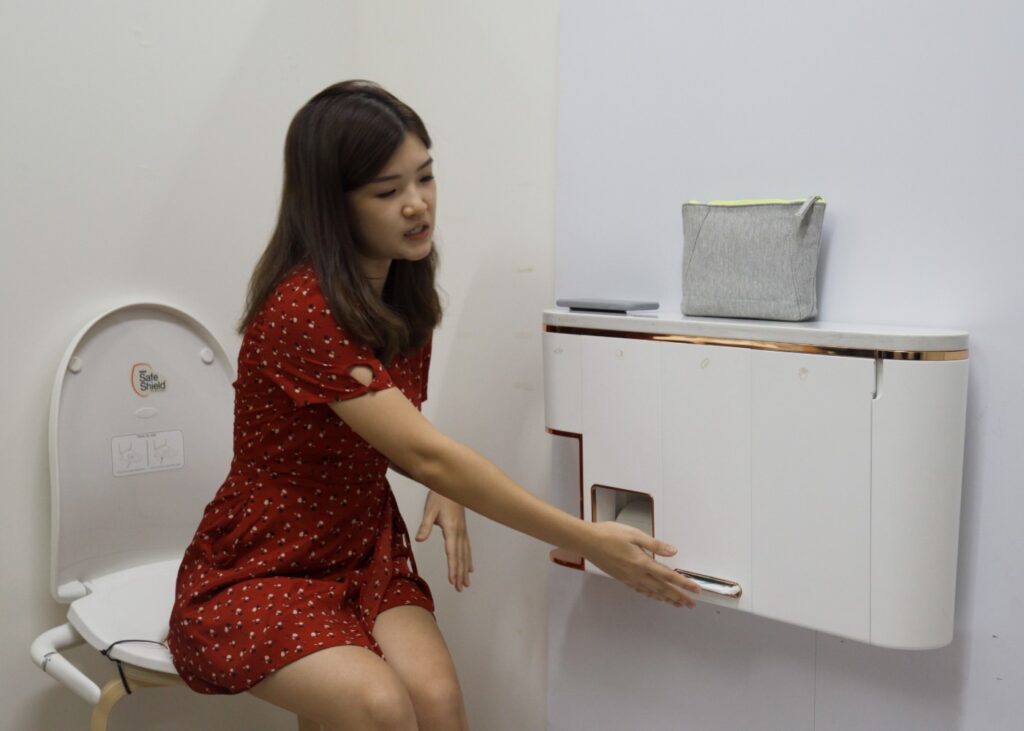 woman user testing a wall mounted restroom gadget for women