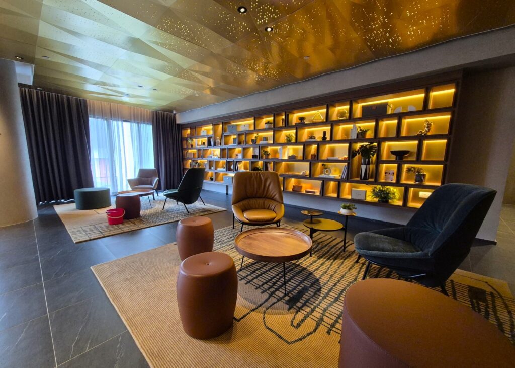 a room with a long bookshelf and relaxing faux-leather lounge seating