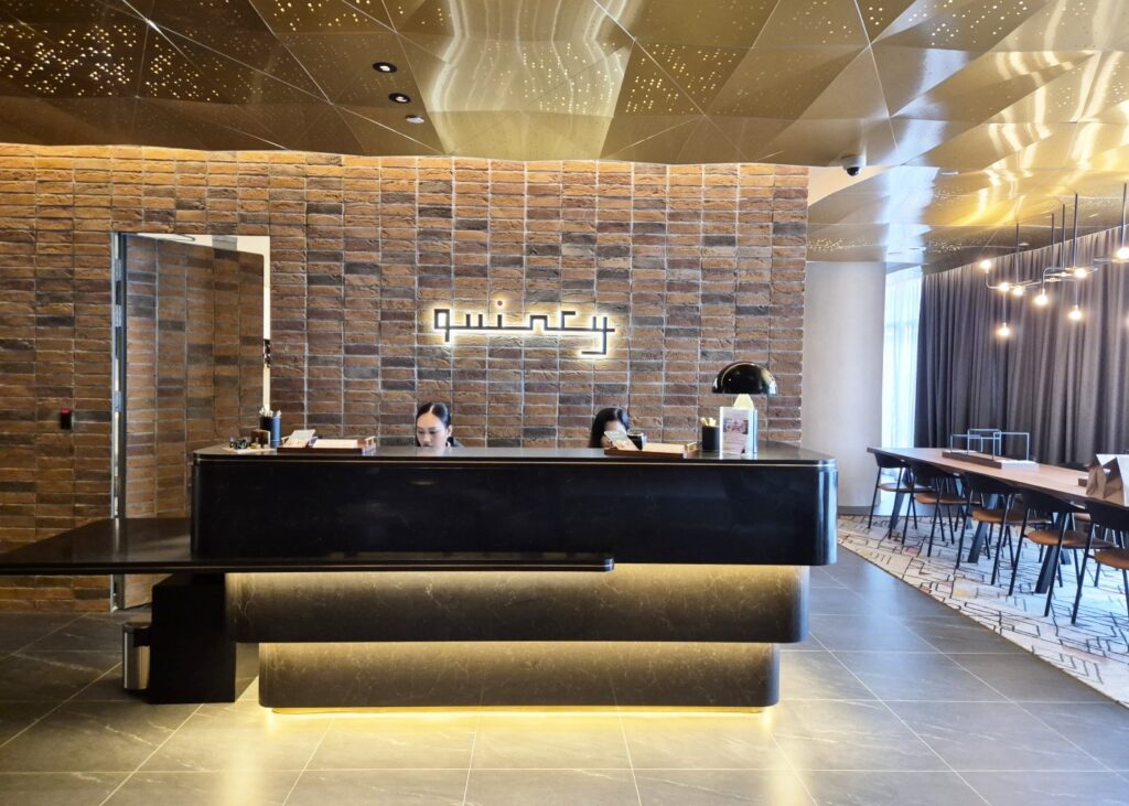 view of a chic black front desk of a hotel with a brick wall background